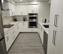Custom U-shaped kitchen with breakfast bar, Hillsboro Beach, Florida, featuring OneSkin Sunny White Super Matte flush-panel cabinetry and Tuscani Quartz countertops.